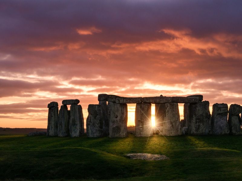 Stonehenge silhouetted against a vibrant sunrise sky.