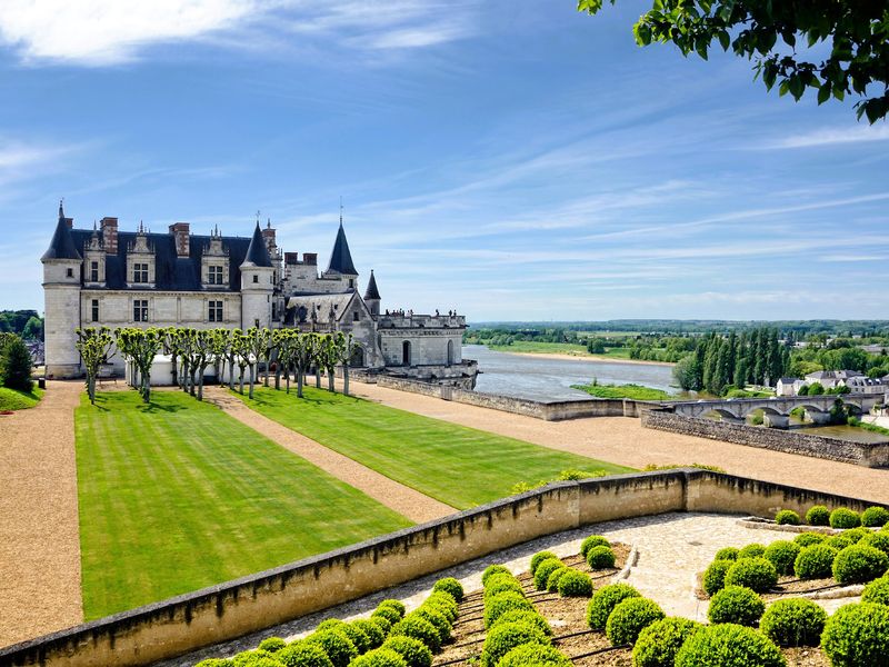 Scenic view of a white castle with manicured lawns and a river.