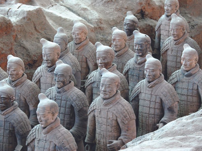 A close-up view of several terracotta soldiers from the Terracotta Army in Xi'an, China. The soldiers, varying in headwear and details, stand in formation, exhibiting the craftsmanship and historical significance of this ancient wonder.