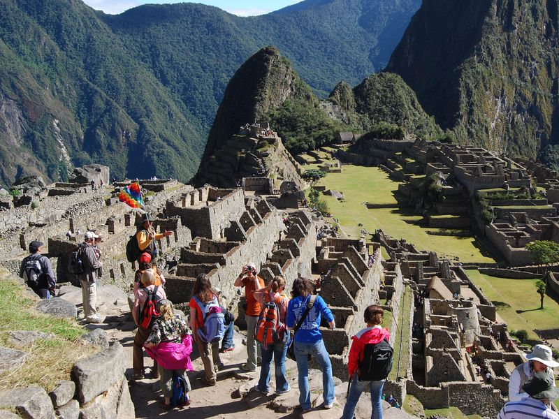 A group of tourists explores the ancient Inca citadel of Machu Picchu, perched high in the Andes Mountains of Peru.